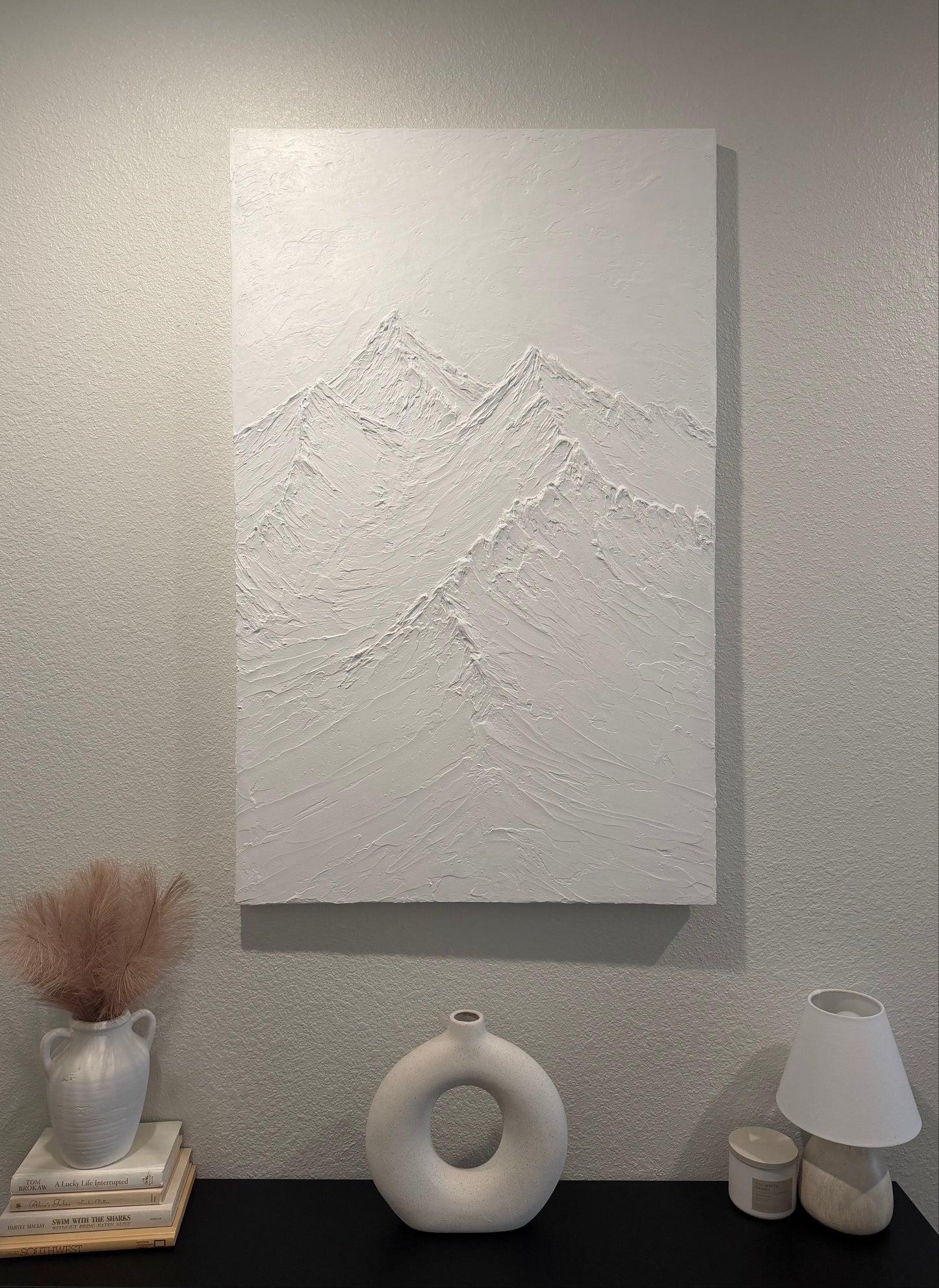 Abstract white painting on a gray wall with decorative vases.