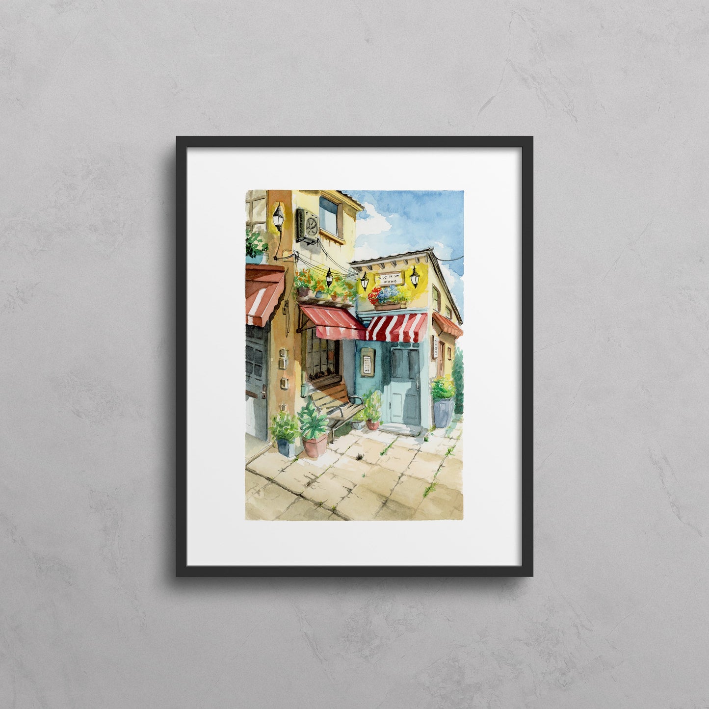 Framed artwork of a colorful street scene on a gray wall
