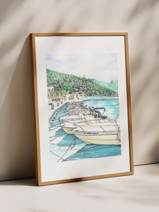 Framed artwork of a coastal scene with boats on a white wall